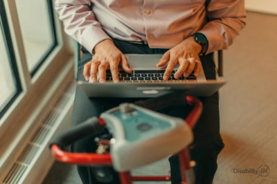 Close up shot of man typing on laptop on his motorized scooter