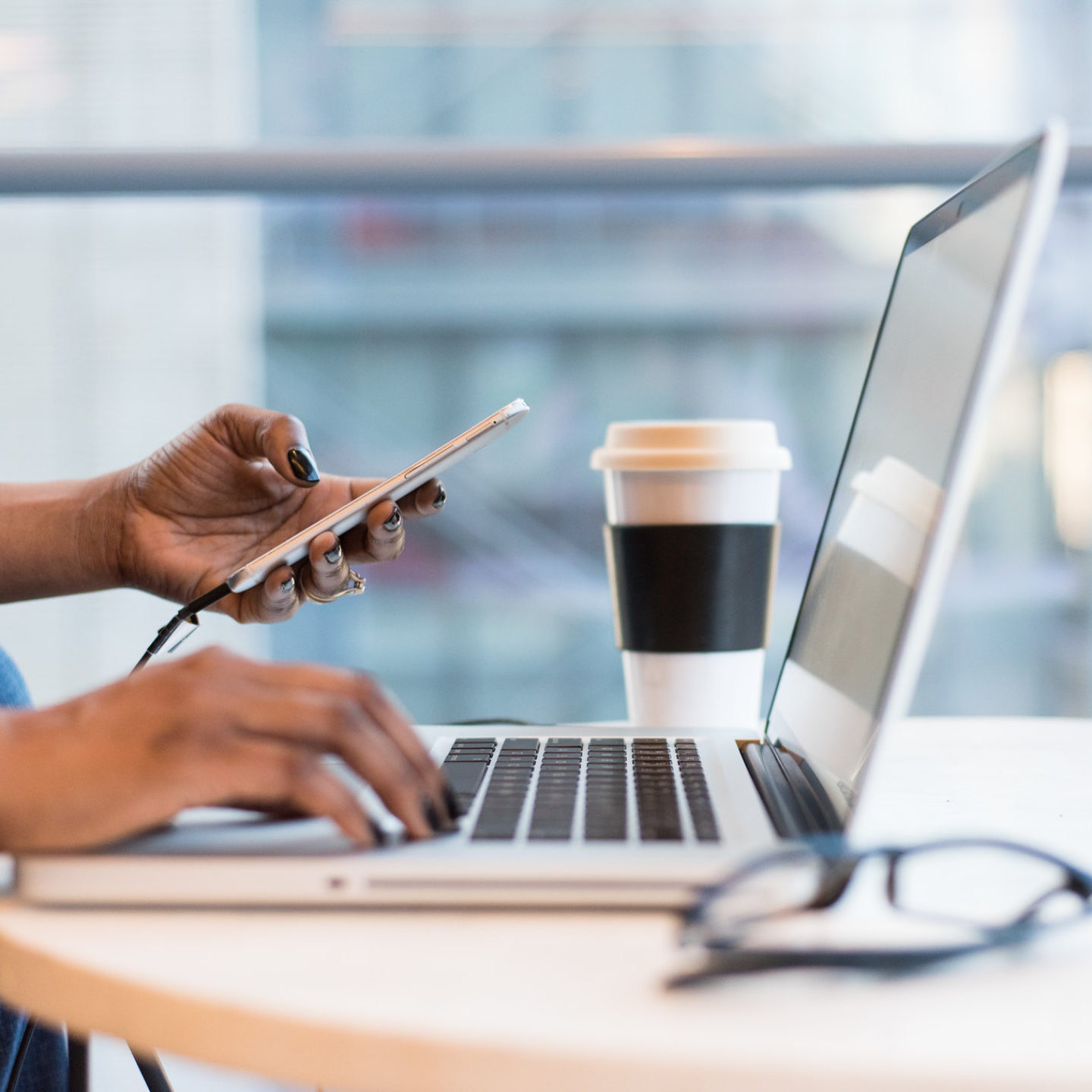 Multitasking at a remote work station on laptop and cellphone.